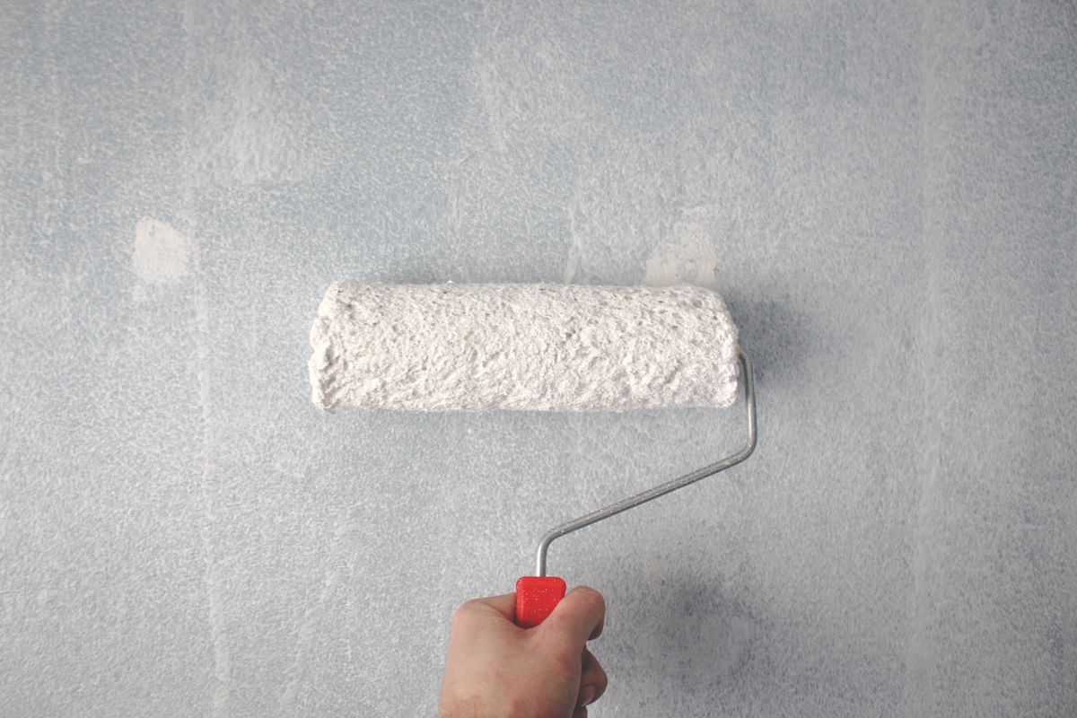 Close-up van een verfroller met witte verf op de muur